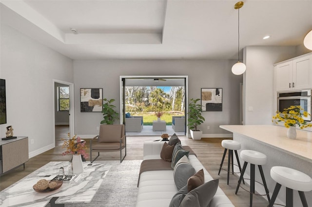 living room with a tray ceiling, hardwood / wood-style flooring, and a wealth of natural light