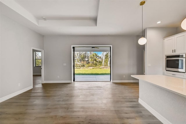 interior space with white cabinetry, a raised ceiling, dark hardwood / wood-style flooring, decorative light fixtures, and oven