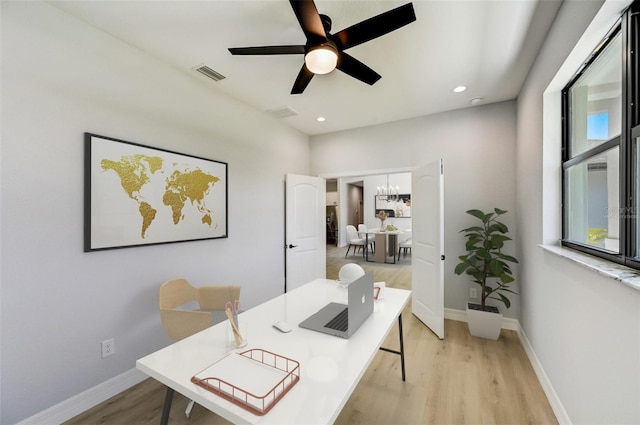 home office with ceiling fan with notable chandelier and light hardwood / wood-style floors