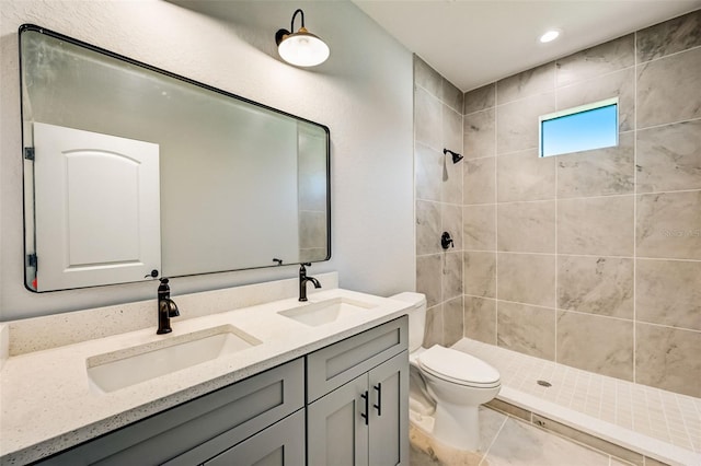 bathroom with vanity, toilet, and a tile shower