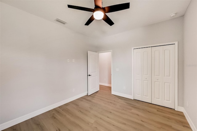 unfurnished bedroom featuring ceiling fan, a closet, and light wood-type flooring