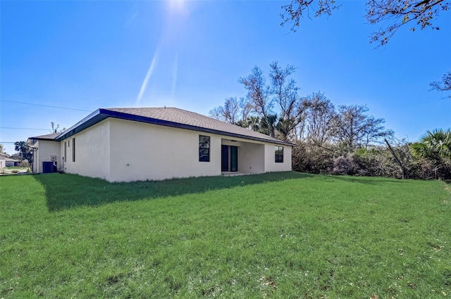 rear view of house featuring central AC unit and a lawn