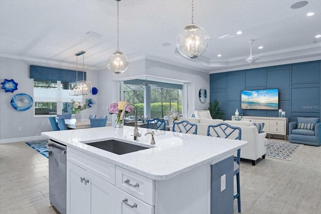 kitchen featuring dishwasher, white cabinetry, sink, hanging light fixtures, and a center island with sink