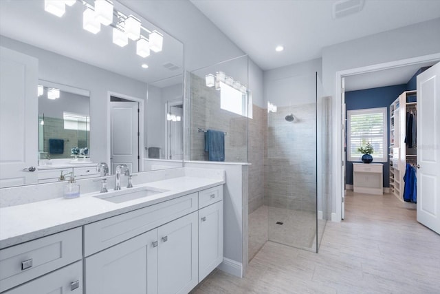 bathroom featuring tiled shower and vanity