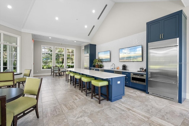 kitchen featuring a kitchen breakfast bar, blue cabinetry, a center island, high vaulted ceiling, and stainless steel appliances