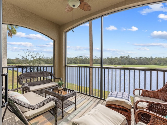 sunroom / solarium with ceiling fan and a water view