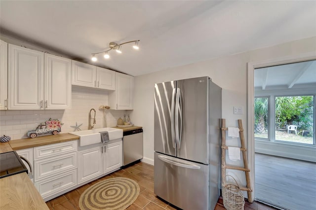 kitchen featuring appliances with stainless steel finishes, white cabinets, tasteful backsplash, and sink