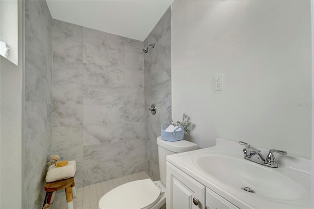 bathroom with toilet, vanity, and a tile shower