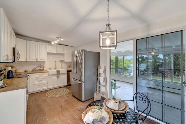 kitchen with appliances with stainless steel finishes, white cabinetry, decorative light fixtures, and sink