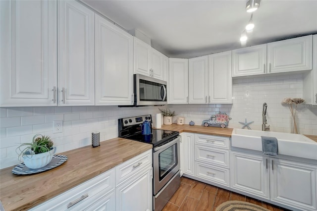 kitchen featuring appliances with stainless steel finishes, white cabinetry, and butcher block countertops