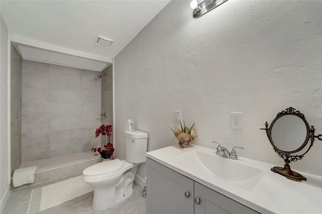 bathroom featuring toilet, tile patterned flooring, a tile shower, and vanity