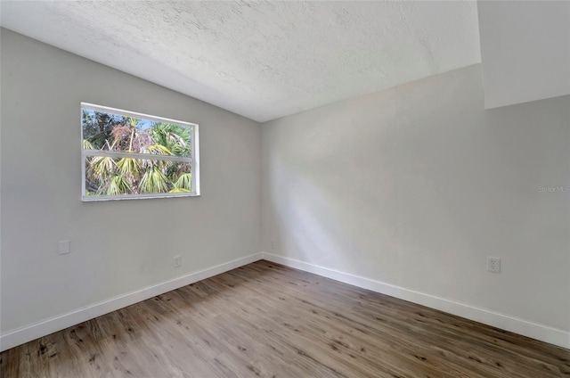 spare room featuring hardwood / wood-style flooring, a textured ceiling, and lofted ceiling