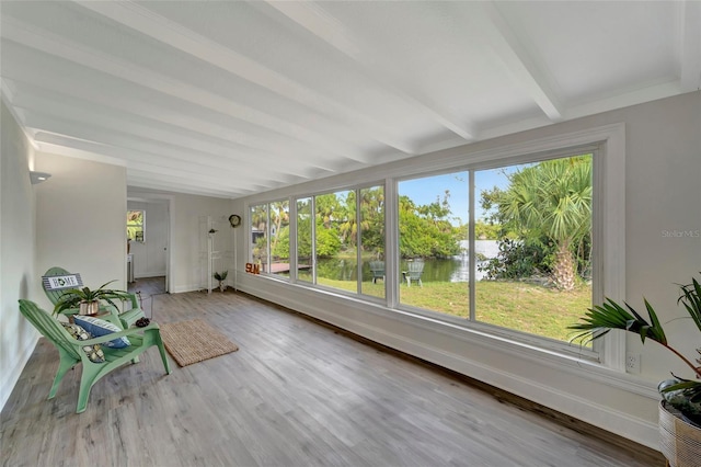 unfurnished sunroom featuring a water view, a healthy amount of sunlight, and beam ceiling