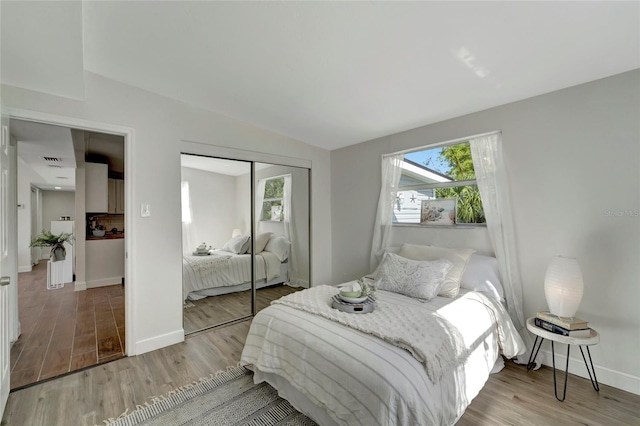 bedroom featuring light wood-type flooring, a closet, and lofted ceiling