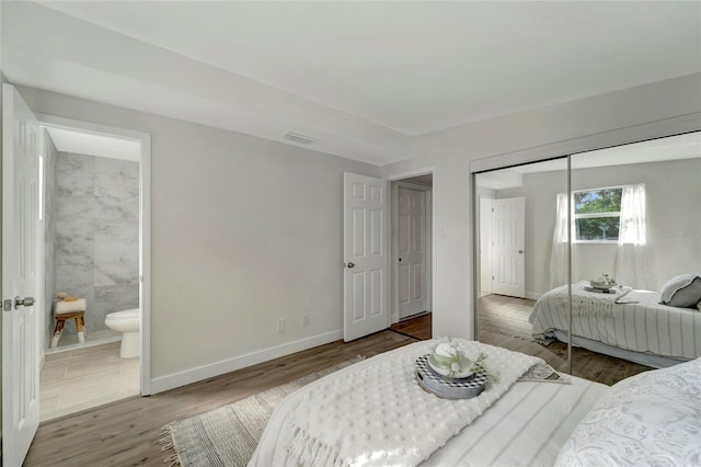 bedroom featuring a closet, hardwood / wood-style floors, and ensuite bath