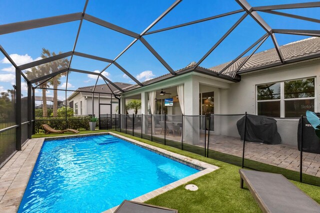 view of pool featuring ceiling fan, a grill, glass enclosure, and a patio area