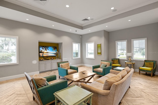 living room with a tray ceiling, ornamental molding, and light parquet floors