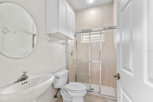 bathroom featuring a shower with shower door, sink, toilet, and tile patterned flooring