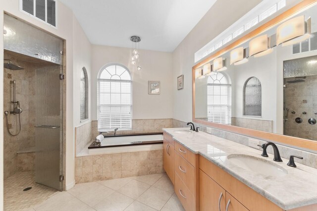 bathroom with plus walk in shower, a healthy amount of sunlight, tile patterned floors, and vanity