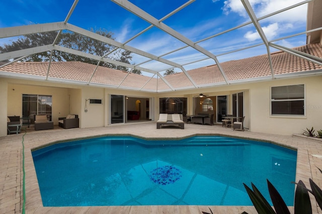 view of pool featuring glass enclosure, outdoor lounge area, ceiling fan, and a patio