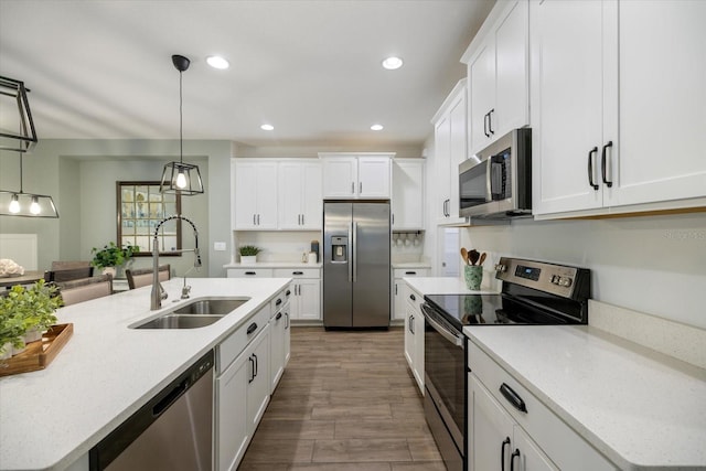 kitchen featuring recessed lighting, a sink, appliances with stainless steel finishes, white cabinetry, and decorative light fixtures