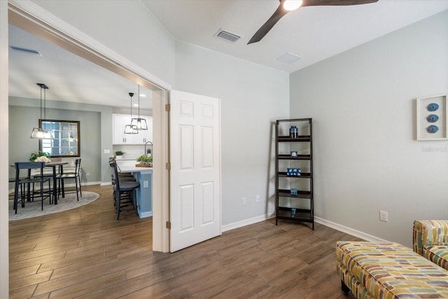 living area featuring visible vents, baseboards, ceiling fan, and dark wood-style flooring