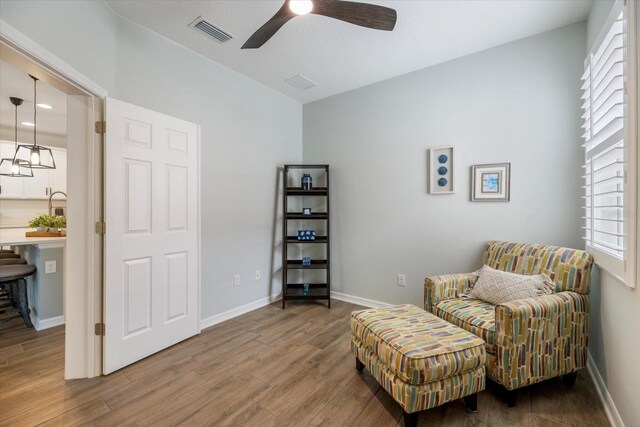 sitting room featuring visible vents, ceiling fan, baseboards, and wood finished floors