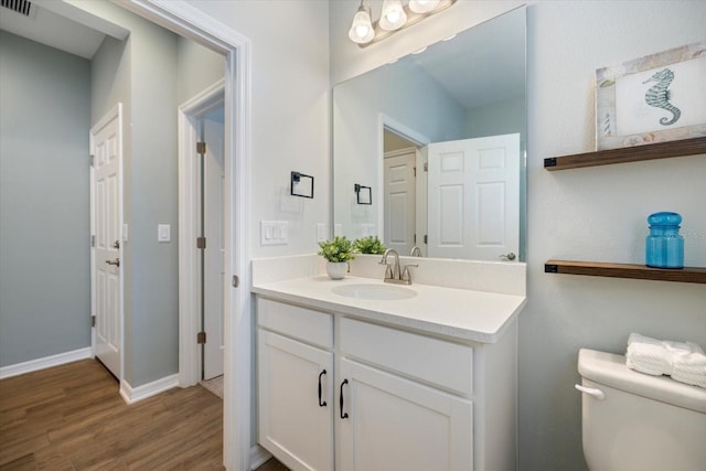 bathroom with wood-type flooring, vanity, and toilet