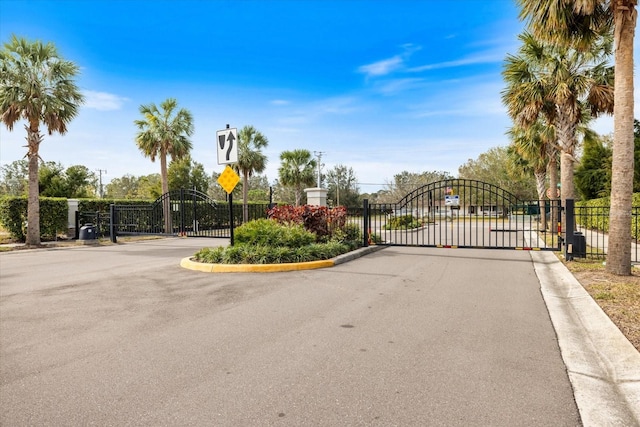 view of street featuring a gated entry, curbs, traffic signs, and a gate