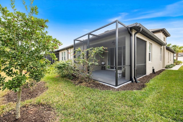 rear view of property with a lanai, a patio area, a yard, and stucco siding