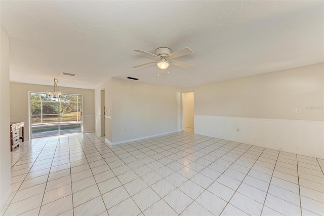 spare room with ceiling fan with notable chandelier, a textured ceiling, and light tile patterned floors