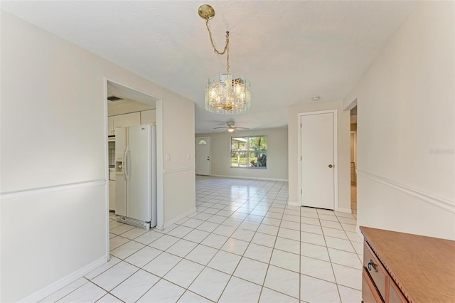 unfurnished dining area with ceiling fan with notable chandelier and light tile patterned floors