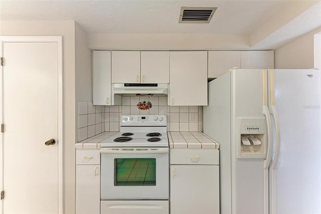 kitchen with tasteful backsplash, tile countertops, white appliances, and white cabinetry