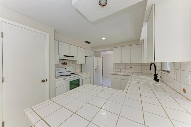 kitchen with white appliances, white cabinets, tasteful backsplash, sink, and tile countertops