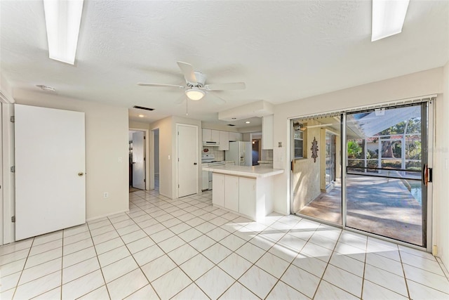 kitchen featuring white appliances, white cabinets, kitchen peninsula, light tile patterned flooring, and ceiling fan