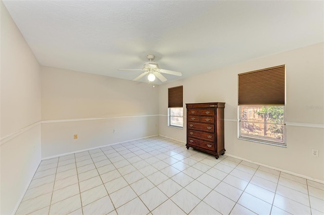 empty room with ceiling fan and light tile patterned floors