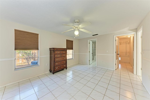 unfurnished bedroom with ceiling fan, connected bathroom, and light tile patterned flooring