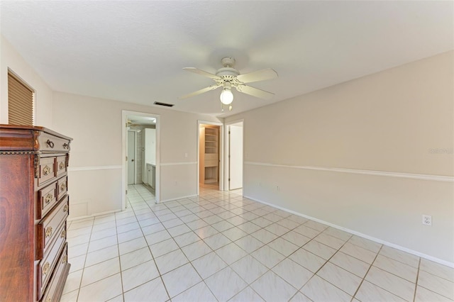 unfurnished bedroom featuring ceiling fan, ensuite bath, and light tile patterned flooring