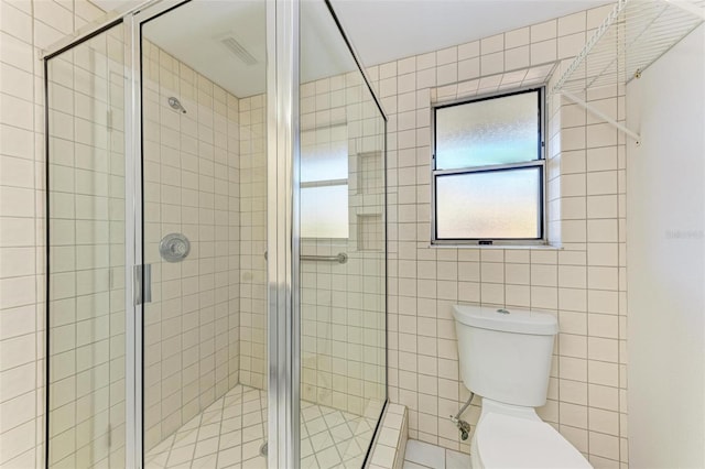 bathroom with toilet, tile walls, and a shower with shower door