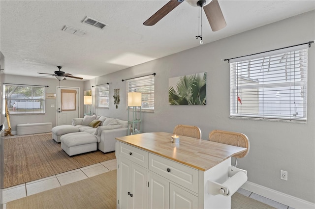 kitchen featuring light tile patterned flooring, butcher block counters, visible vents, white cabinets, and open floor plan