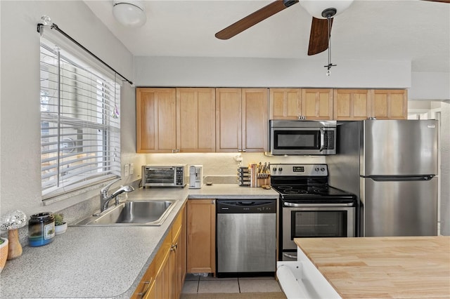 kitchen featuring light tile patterned floors, ceiling fan, a toaster, a sink, and appliances with stainless steel finishes