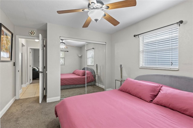 bedroom with light carpet, a ceiling fan, baseboards, and a closet