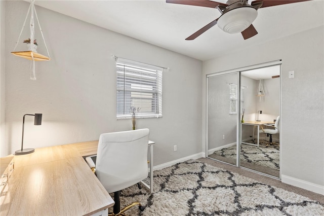 carpeted office featuring baseboards and a ceiling fan