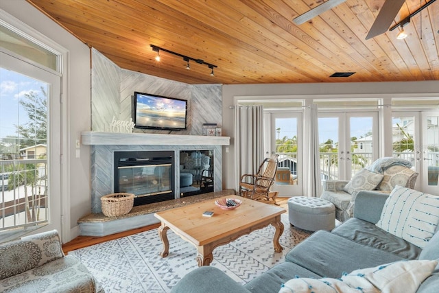 living room with wooden ceiling, ceiling fan, track lighting, a fireplace, and french doors