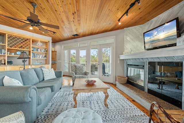 living room with rail lighting, wood walls, wooden ceiling, wood-type flooring, and a high end fireplace