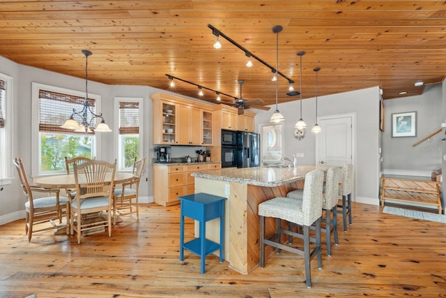 kitchen featuring wood ceiling, light stone counters, pendant lighting, and a kitchen island with sink