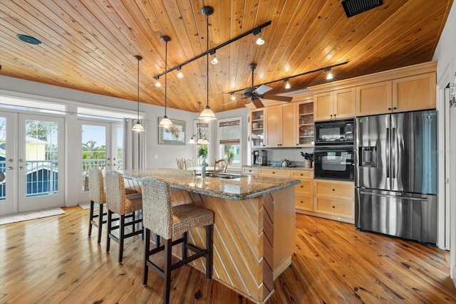 kitchen featuring decorative light fixtures, black appliances, french doors, dark stone counters, and rail lighting