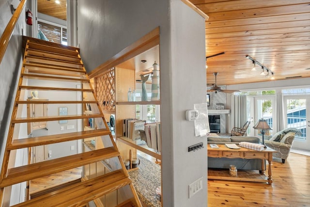 stairway with wooden ceiling, rail lighting, hardwood / wood-style flooring, and ceiling fan