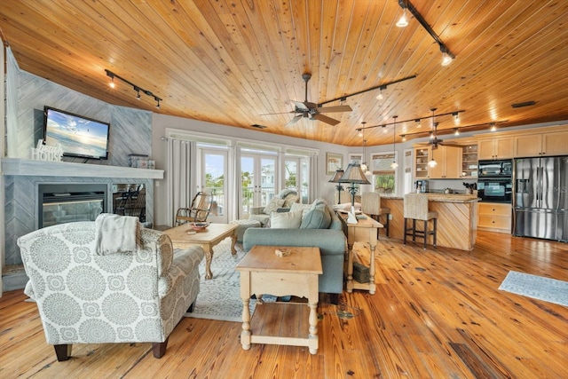 living room featuring a fireplace, wood ceiling, wooden walls, and rail lighting