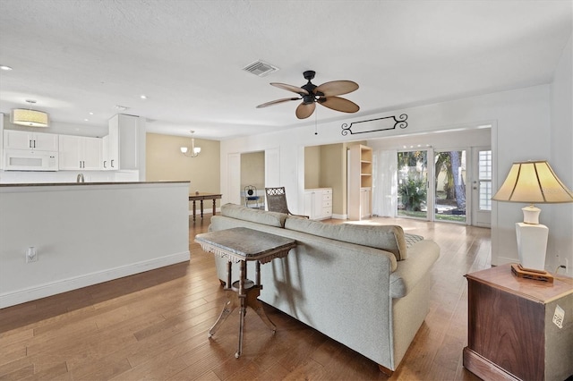 living room featuring a textured ceiling, ceiling fan with notable chandelier, and hardwood / wood-style flooring